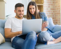 appy young couple in new home using laptop to interpret results and manage their family's health information.