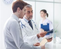 Doctor helping patient interpret X-ray results during a medical consultation.