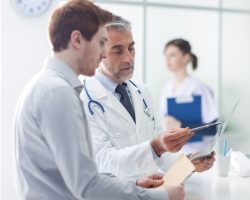 Doctor helping patient interpret X-ray results during a medical consultation.